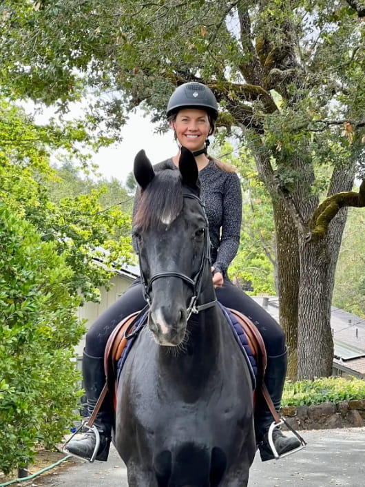 Dr. Jacqueline riding a black horse outdoors