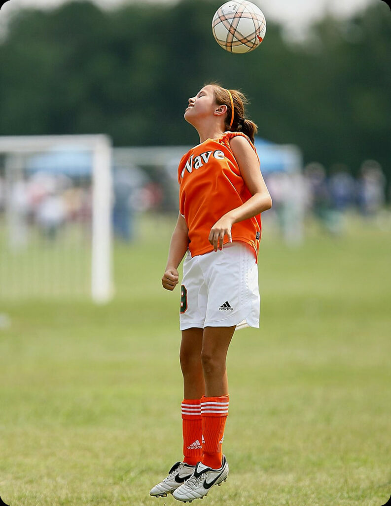 Girl juggling soccer ball in air